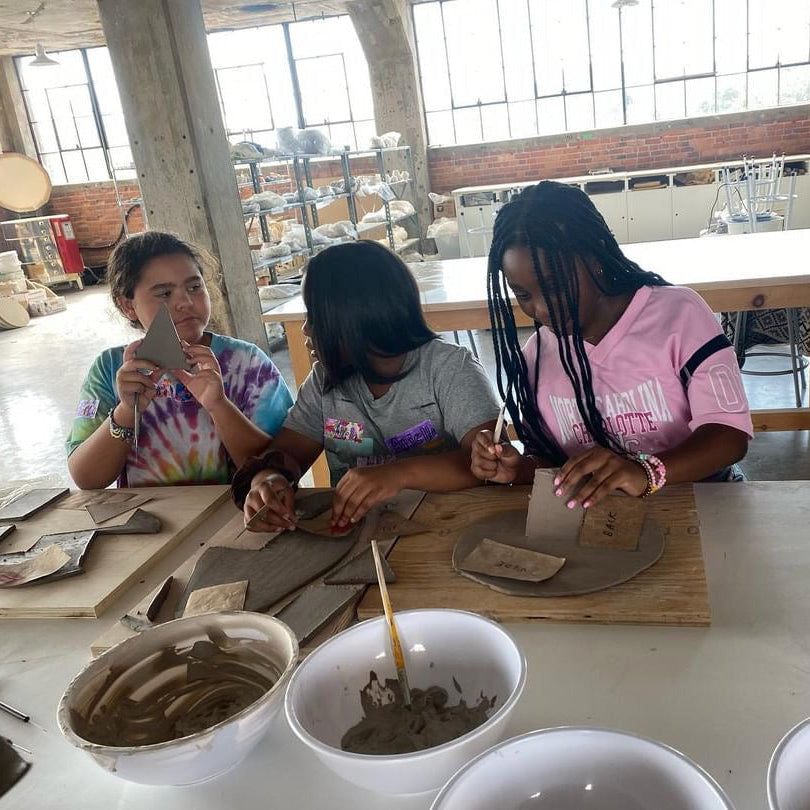 Three people working with clay in a pottery studio.