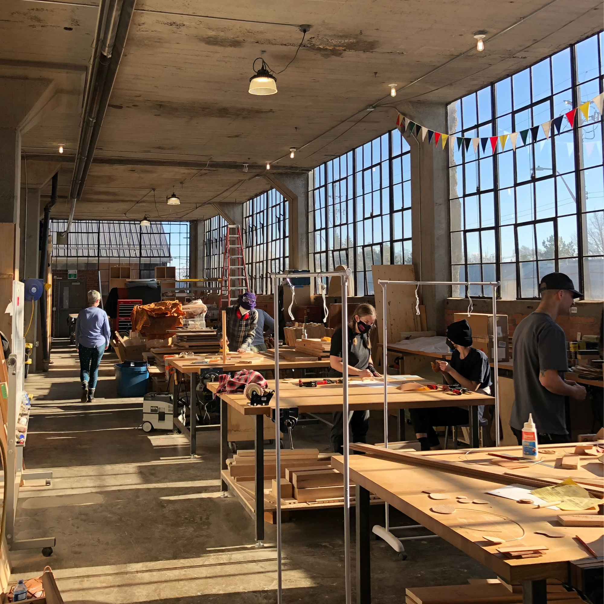 Hamilton Craft Studios maker space, large open space with worksurfaces and tall old-timey warehouse windows.