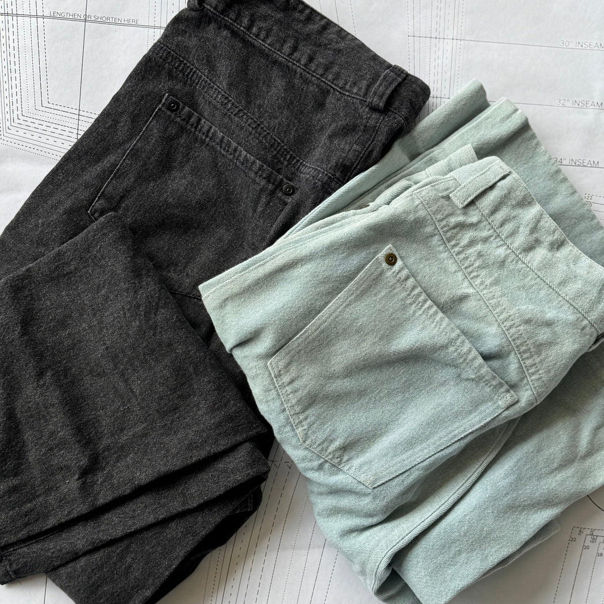 light and dark denim jeans sitting folded on top of a printed pattern sheet